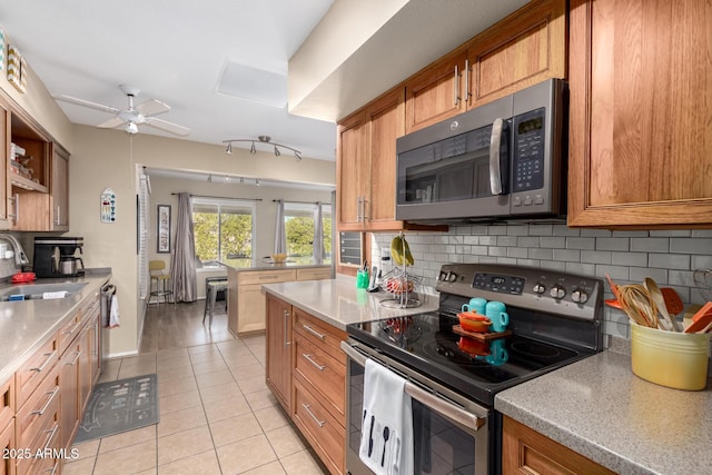 kitchen featuring sink, light tile patterned floors, ceiling fan, stainless steel appliances, and backsplash