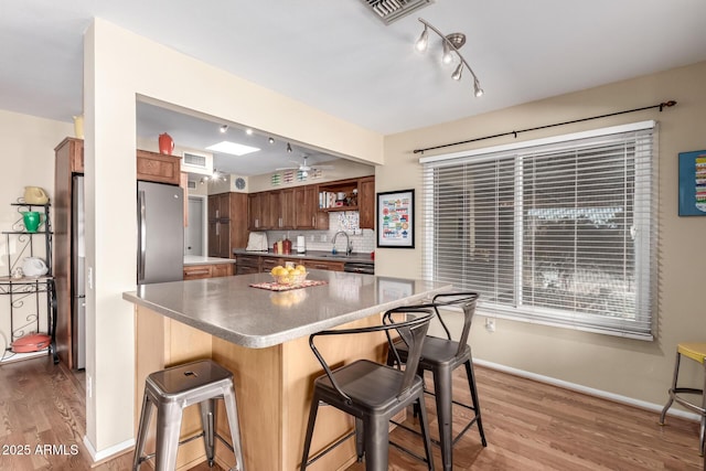 kitchen with sink, a breakfast bar, stainless steel refrigerator, hardwood / wood-style floors, and tasteful backsplash