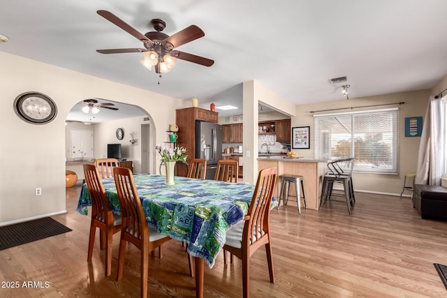 dining space featuring ceiling fan, sink, and light hardwood / wood-style floors