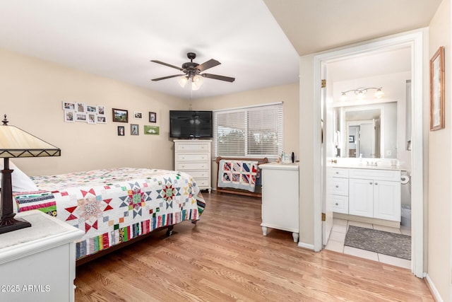 bedroom with ceiling fan, sink, light wood-type flooring, and ensuite bath