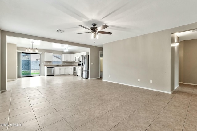 unfurnished living room featuring sink, ceiling fan with notable chandelier, and light tile patterned flooring