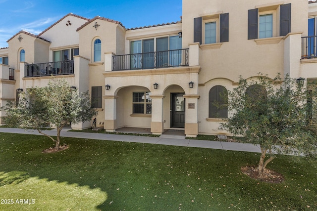 view of front of house with a tile roof, a front lawn, and stucco siding