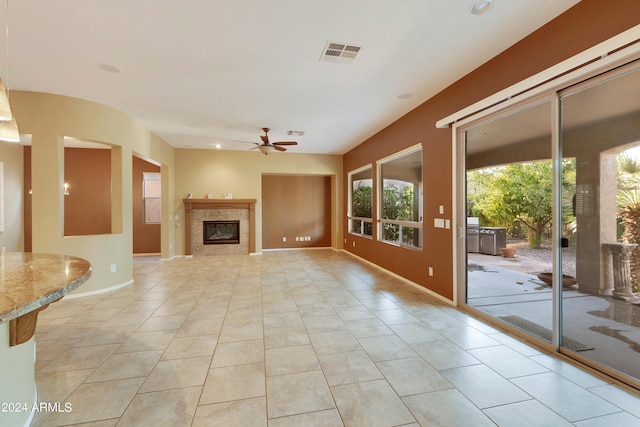 unfurnished living room with visible vents, a glass covered fireplace, light tile patterned floors, baseboards, and ceiling fan