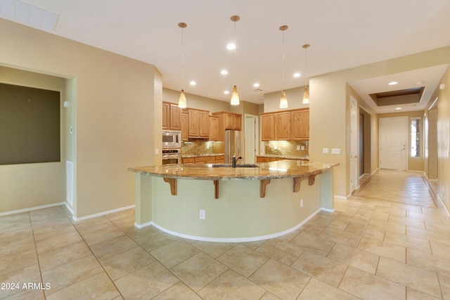 kitchen with visible vents, a sink, backsplash, appliances with stainless steel finishes, and a breakfast bar area