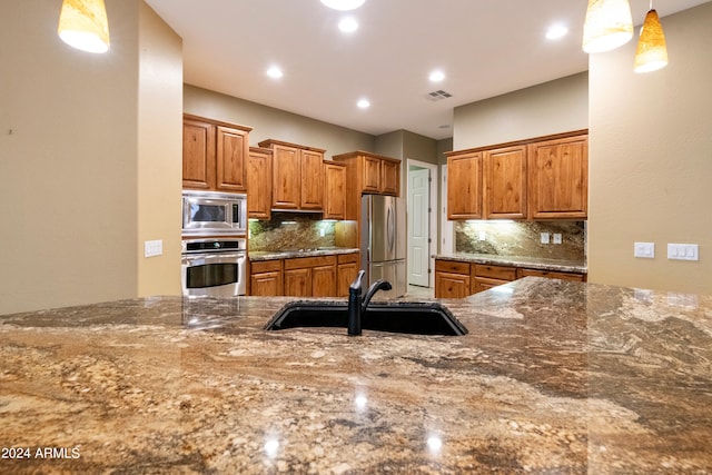 kitchen featuring visible vents, brown cabinets, stainless steel appliances, and a sink