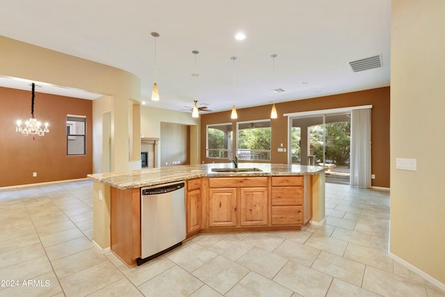 kitchen with visible vents, a sink, stainless steel dishwasher, a fireplace, and light stone countertops