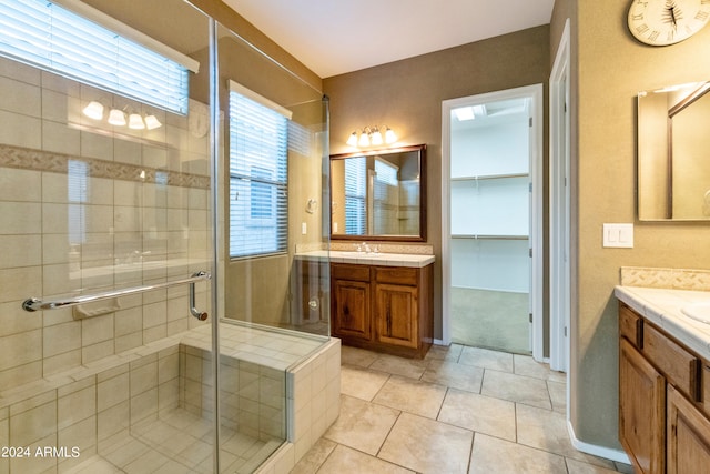 bathroom with tile patterned flooring, a spacious closet, a shower stall, two vanities, and a sink