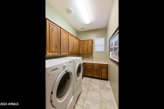 clothes washing area featuring light tile patterned floors, cabinet space, baseboards, and washer and clothes dryer