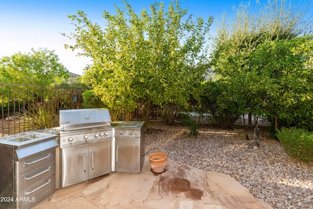 view of patio / terrace with exterior kitchen, fence, and a grill