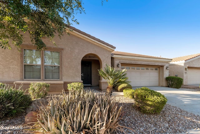 view of front of home with stucco siding, concrete driveway, and an attached garage