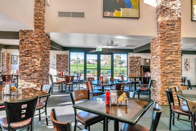 dining room featuring visible vents, a towering ceiling, and decorative columns