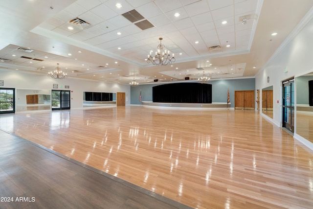 exercise room with visible vents, ornamental molding, an inviting chandelier, wood finished floors, and a raised ceiling