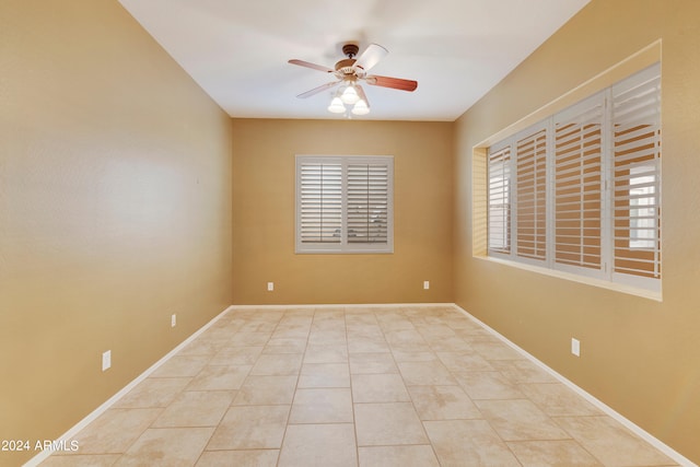 unfurnished room with tile patterned floors, a ceiling fan, and baseboards