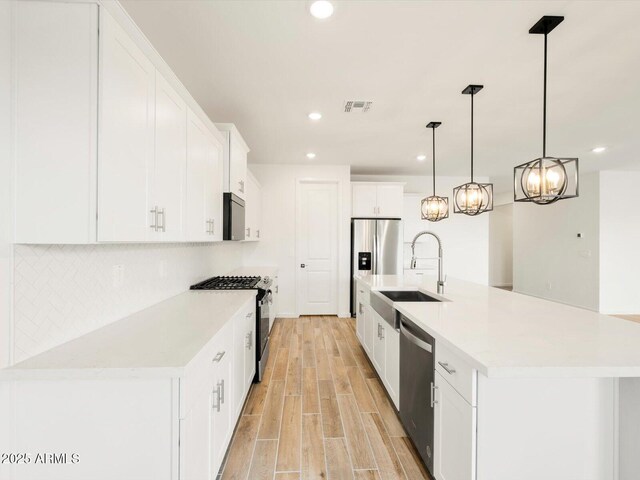 kitchen with light wood-type flooring, backsplash, visible vents, appliances with stainless steel finishes, and a sink