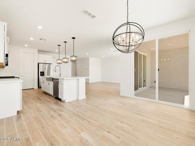 kitchen featuring a notable chandelier, light wood-type flooring, open floor plan, visible vents, and appliances with stainless steel finishes