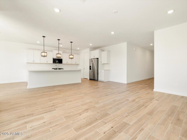 unfurnished living room with a sink, recessed lighting, and light wood-style floors
