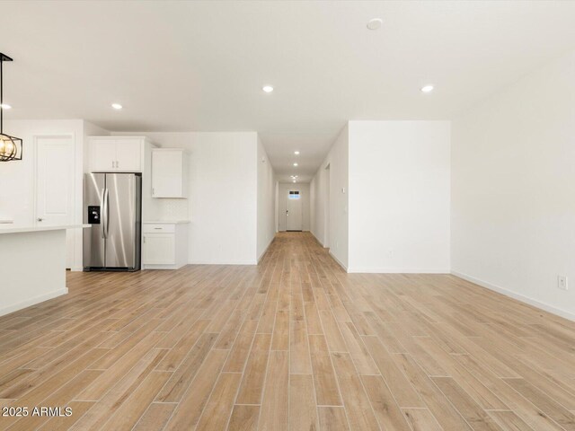 unfurnished living room with baseboards, recessed lighting, a notable chandelier, and light wood-style floors