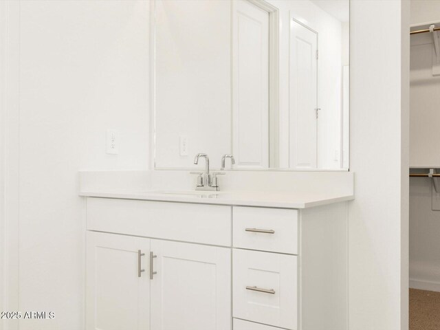 bathroom featuring a spacious closet and vanity