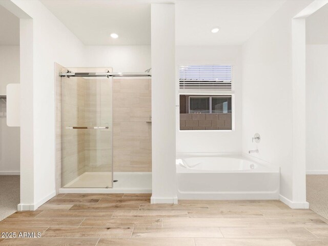 bathroom featuring baseboards, a garden tub, a stall shower, and wood tiled floor
