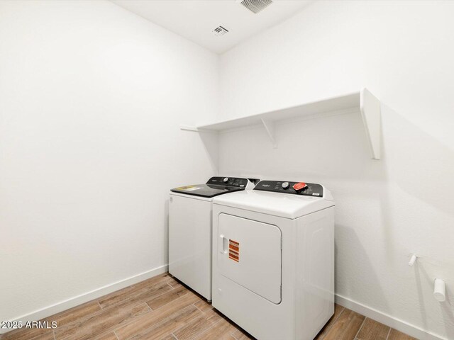 laundry area with light wood finished floors, laundry area, washing machine and clothes dryer, and baseboards