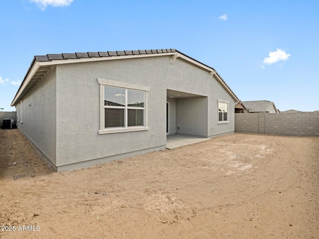 rear view of house featuring a patio area, central air condition unit, a fenced backyard, and stucco siding