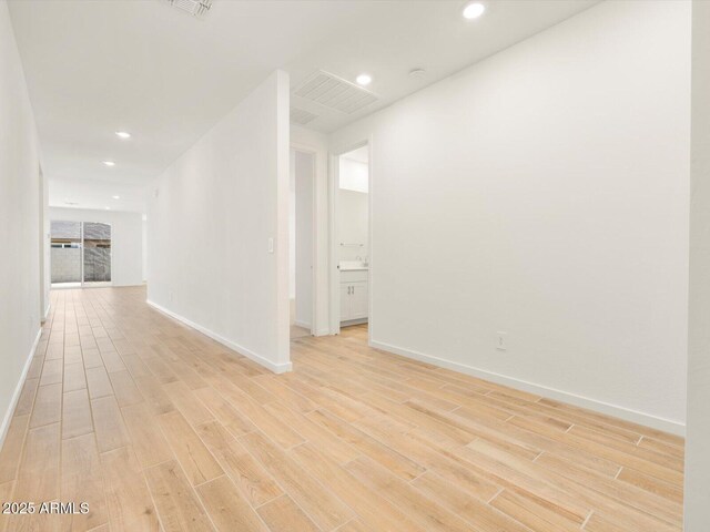 empty room with light wood-style floors, baseboards, visible vents, and recessed lighting