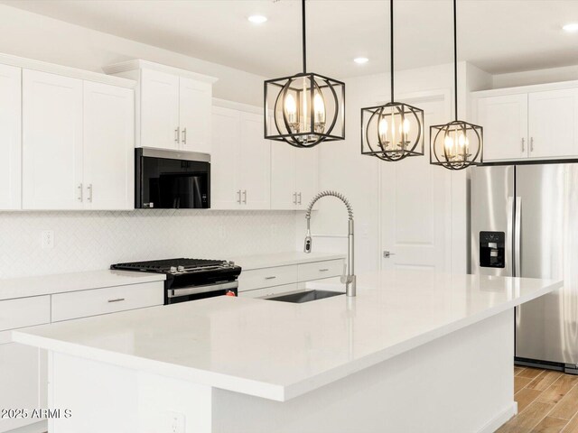 kitchen with stainless steel fridge, black microwave, gas range, decorative backsplash, and a sink