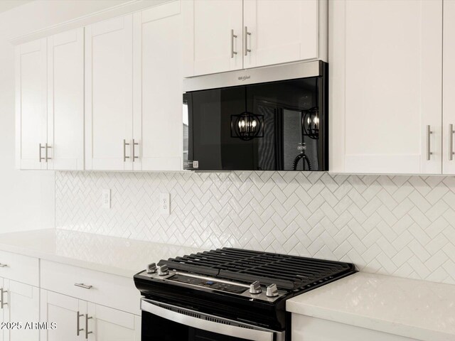 kitchen featuring tasteful backsplash, stainless steel gas range, and white cabinets