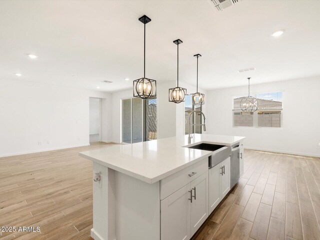 kitchen with visible vents, dishwasher, a sink, a chandelier, and light wood finished floors