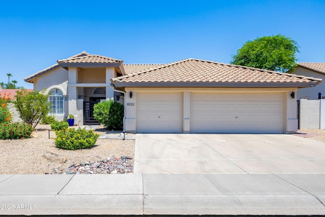 view of front of property featuring a tiled roof, a garage, driveway, and stucco siding