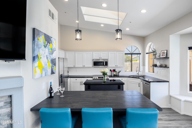 kitchen with visible vents, a sink, appliances with stainless steel finishes, white cabinetry, and dark countertops