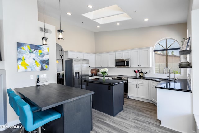 kitchen featuring visible vents, a skylight, a sink, appliances with stainless steel finishes, and dark countertops