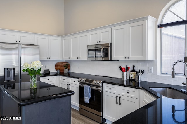 kitchen featuring white cabinets, wood finished floors, tasteful backsplash, and stainless steel appliances