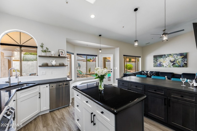 kitchen featuring dark countertops, a sink, a center island, dishwasher, and open shelves