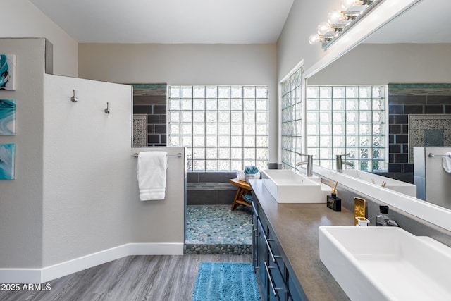 full bathroom with walk in shower, wood finished floors, baseboards, and a sink