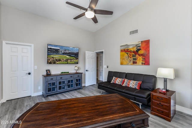 living area with visible vents, high vaulted ceiling, a ceiling fan, light wood finished floors, and baseboards