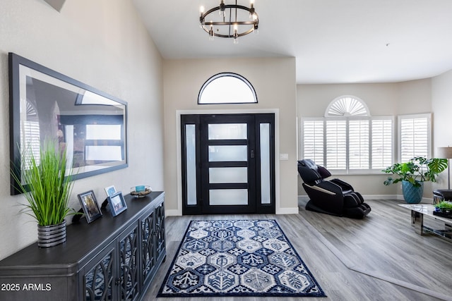 foyer featuring baseboards, a notable chandelier, and wood finished floors