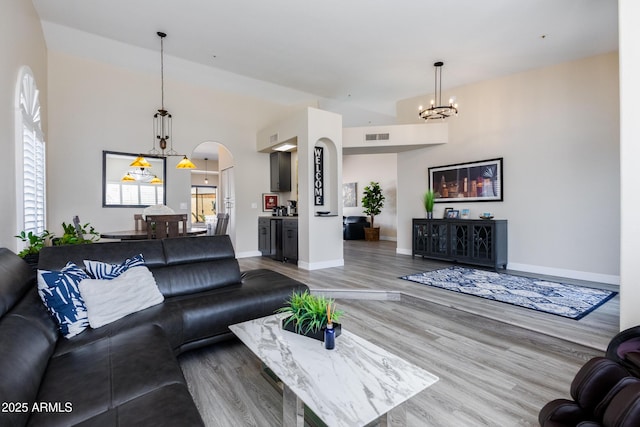 living room with visible vents, wood finished floors, baseboards, and a chandelier