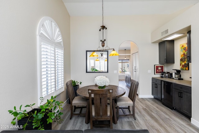 dining area featuring arched walkways, visible vents, baseboards, and light wood-style floors