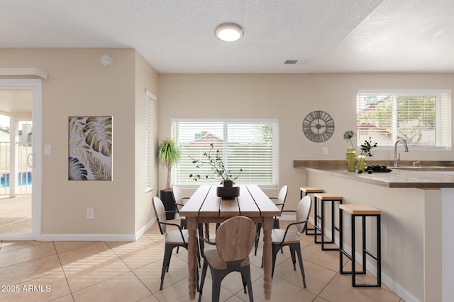 dining room featuring light tile patterned floors, visible vents, a textured ceiling, and baseboards