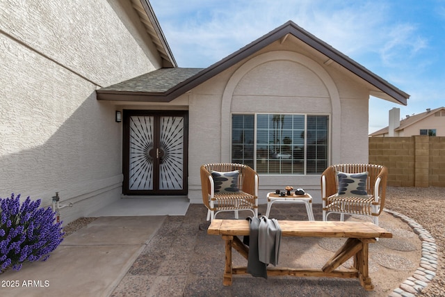 doorway to property featuring stucco siding, a patio, and fence