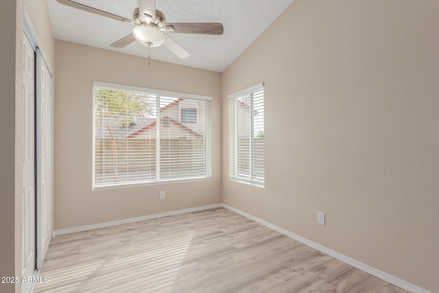 unfurnished room featuring light wood finished floors, a textured ceiling, baseboards, and a ceiling fan