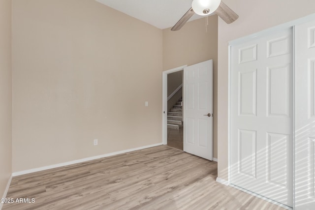 unfurnished room featuring light wood finished floors, stairway, ceiling fan, and baseboards