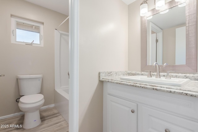 full bathroom featuring toilet, wood finished floors, tub / shower combination, baseboards, and vanity