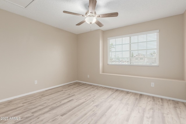 empty room with a ceiling fan, wood finished floors, baseboards, and a textured ceiling