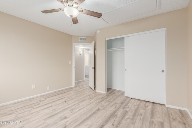 unfurnished bedroom featuring visible vents, baseboards, attic access, light wood-style floors, and a closet