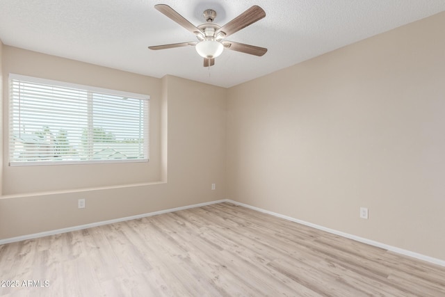 empty room featuring light wood-style flooring, a textured ceiling, and baseboards