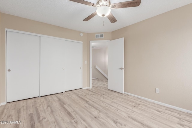 unfurnished bedroom featuring visible vents, light wood-style flooring, a ceiling fan, a closet, and baseboards