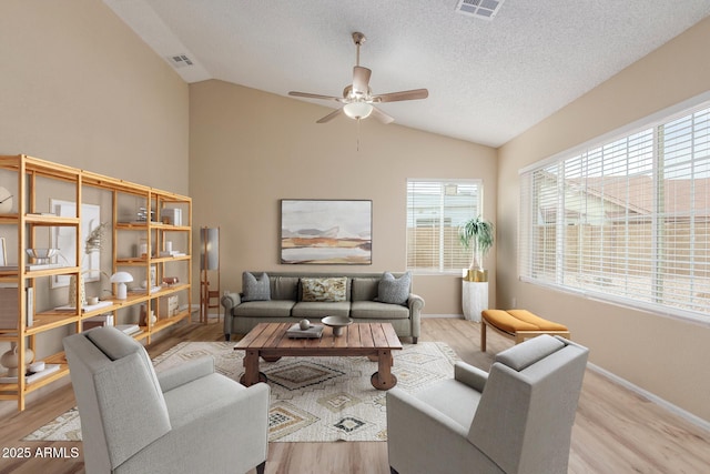 living room featuring visible vents, a textured ceiling, lofted ceiling, and wood finished floors