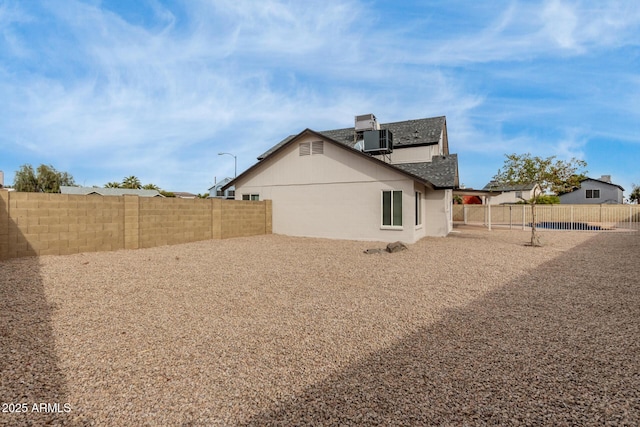 back of property with central AC unit and a fenced backyard